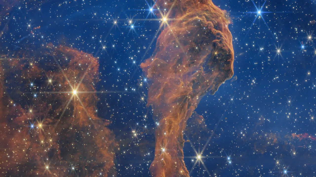 Webbs NIRCam-optagelse af Cat’s Head Nebula med en brunorange støvsøjle og blå og gule stjerner